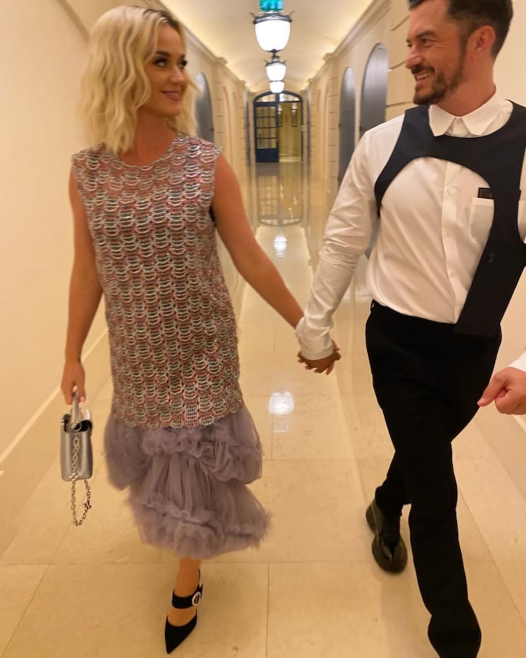 Katy Perry and Orlando Bloom walking in a hallway